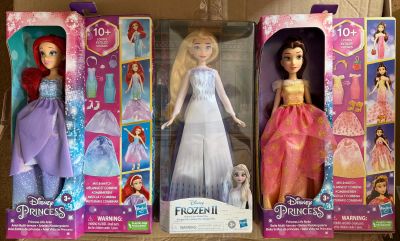 Trois poupées Barbie se trouvent dans une boîte en carton posée sur une table