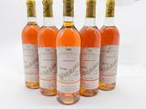 quatre bouteilles de vin sont alignées sur une surface blanche