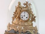 une horloge en or sous un dôme de verre sur une table