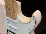 a white electric guitar that is on display in a room