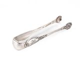 une cuillère ancienne en argent et son repose-cuillère posés sur une surface blanche
