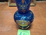 un vase bleu posé sur une table en bois à côté d'un cadre photo
