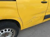 a small yellow car that has been damaged and is parked in a parking lot
