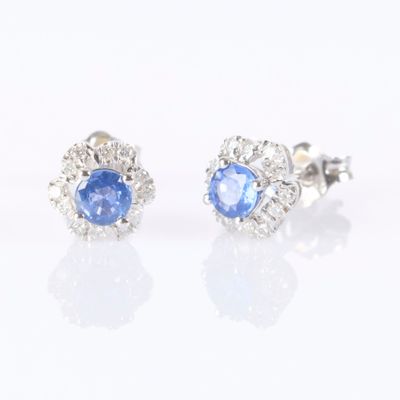 paire de boucles d'oreilles à clous en saphir bleu et diamants sur fond blanc