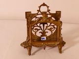 une petite horloge en or posée sur un socle, sur une surface blanche