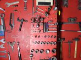 a red wall with a bunch of tools hanging on it