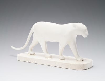 a white sculpture of a cat on a wooden base