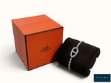une boîte orange contenant un bracelet à maillons et un sac noir