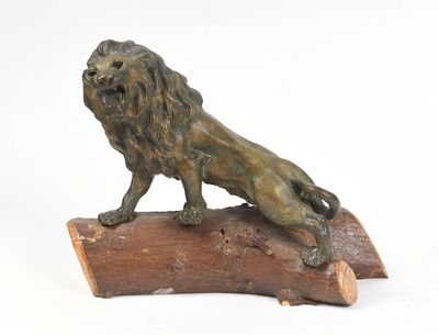 statue en bronze représentant un lion perché sur un tronc d'arbre, sur fond blanc