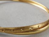 a close up of a gold bracelet with stars on it