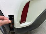 a hand that is holding a measuring tape near a car