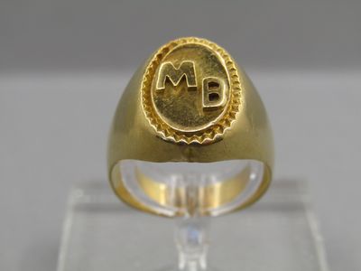 a close up of a gold ring with a monogram on it