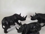 three black rhino figurines sitting next to each other on a white surface