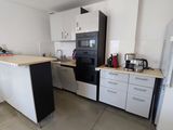 une photo d'une cuisine avec des placards blancs et des appareils électroménagers noirs