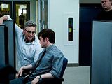 two men sitting in a cubicle talking to each other