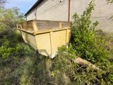une benne jaune posée dans l'herbe à côté d'un immeuble