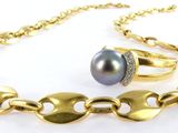 a close up of a gold chain bracelet with a black pearl