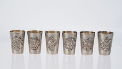 a set of four silver shot glasses with designs on them