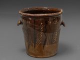 a brown vase with designs on it on a gray surface