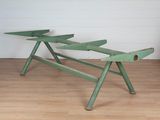 un banc vert posé sur un plancher en bois