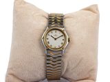 a gold and silver wrist watch on a pillow