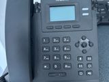 a black phone sitting on a desk next to a computer monitor