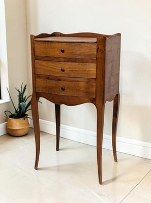 une petite commode dans une pièce où se trouve une plante en pot dans un coin