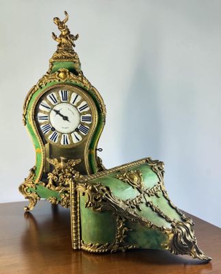 a green and gold clock sitting on a wooden table