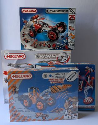 trois boîtes de legos sont empilées sur une surface blanche