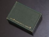 an old green book sitting on top of a table next to a black table