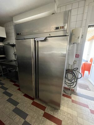 un réfrigérateur en acier inoxydable dans une cuisine au sol en damier