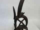 une statue en bronze représentant un oiseau à longue queue posée sur une surface blanche
