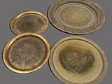 three brass trays with decorative designs on them on a gray surface