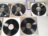 four black vinyl records on a table with a picture of a man in the background