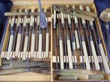 many knives and spoons in a box on a table