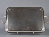 silver tray with handles and handles on a stand on a gray background