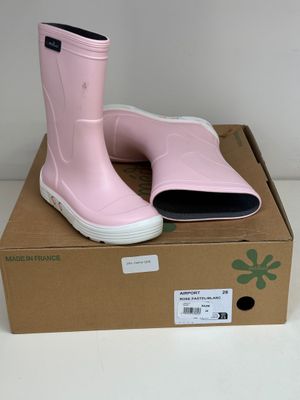une paire de bottes de pluie roses posée sur une boîte en carton