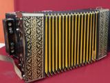 an old black and gold accordion sitting on a red surface