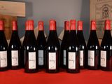 six bottles of red wine are lined up on a red table