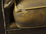 a close up of a brown leather couch with a pillow