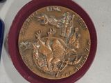 a gold medal on a red plate next to a pair of scissors