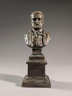 a bronze bust of a man with a bow tie on a pedestal