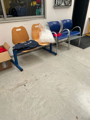 trois chaises dans une salle d'attente, sur lesquelles sont posés des sacs contenant diverses affaires