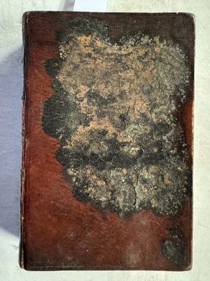 un vieux livre posé sur une table blanche, à côté d'une feuille de papier