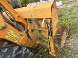 a tractor that is sitting in the grass near a pile of dirt