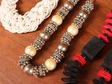 three necklaces on a wooden table with beads and beads