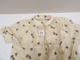 beige shirt with black and white polka dots on it on a white surface