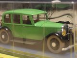 a green toy car in a clear case on a table