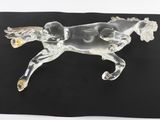 clear glass figurine of a running horse on a black surface