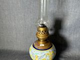 une lampe à huile à l'ancienne, avec un pied doré et un motif bleu et blanc